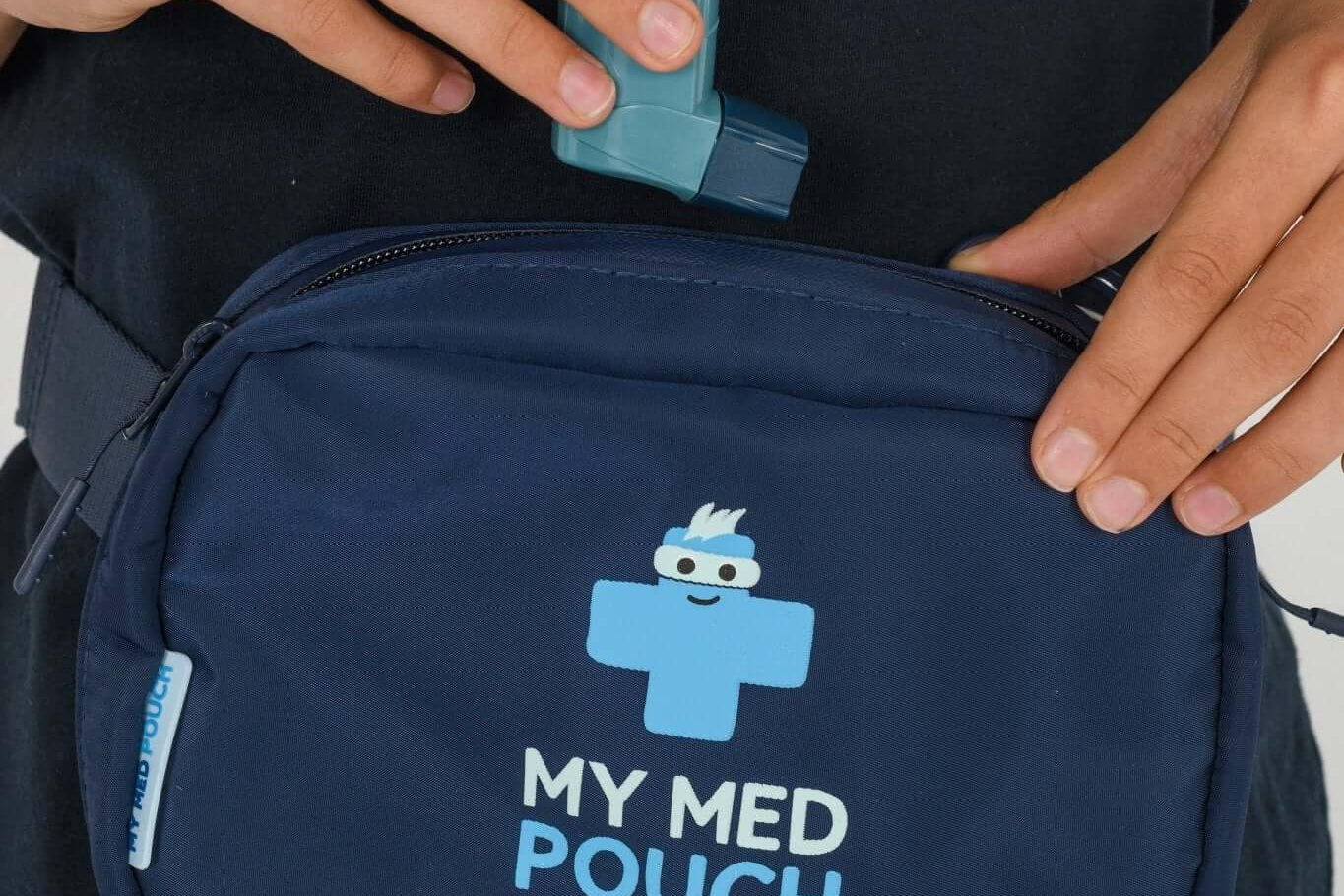 Navy Med Ready Bag being worn as a waist bag with child placing an asthma inhaler in the bag.