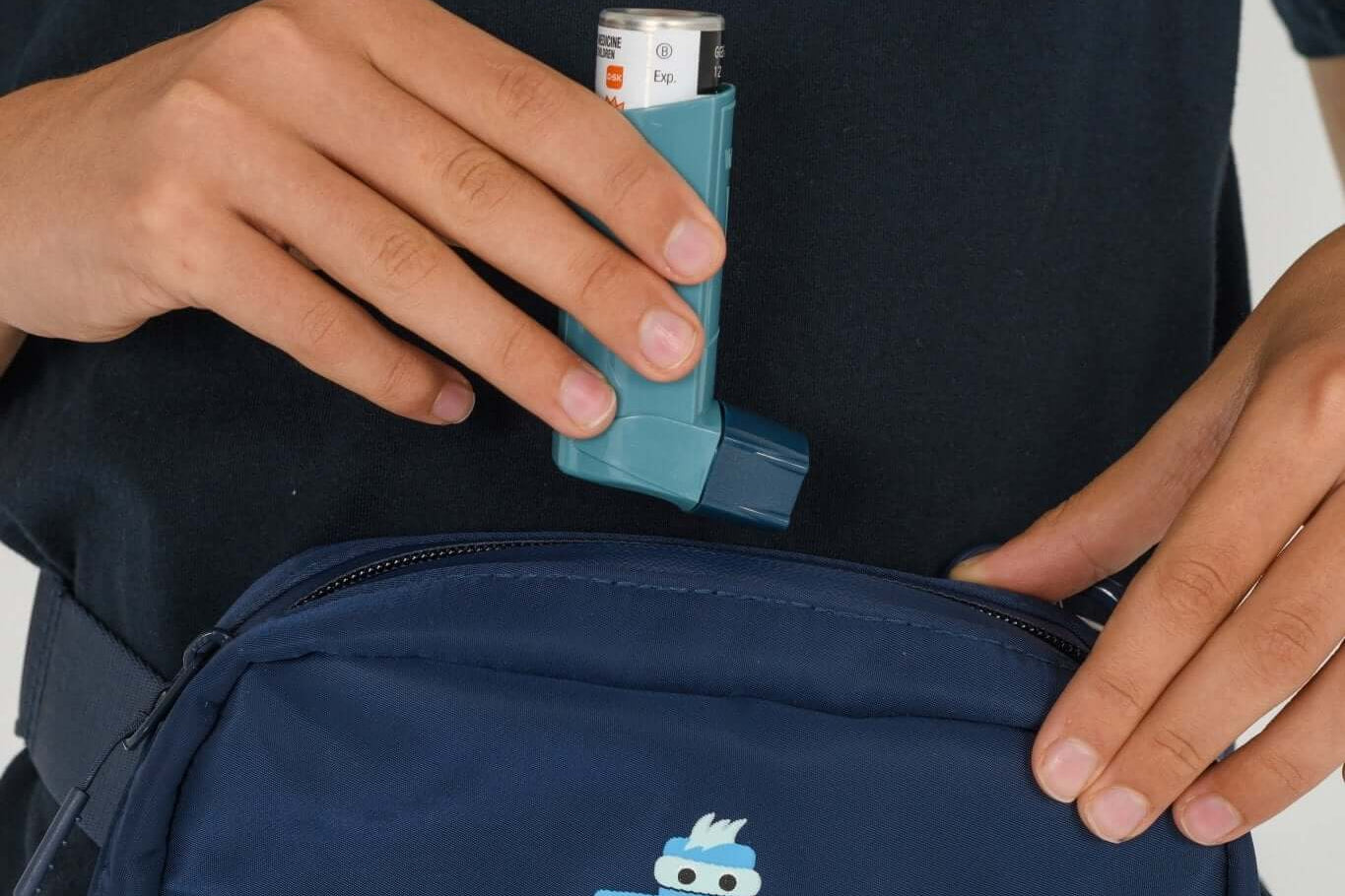 Navy Med Ready Bag being worn as a waist bag with child placing an asthma inhaler in the bag.